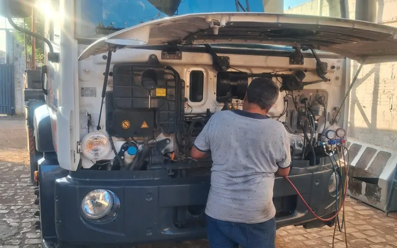 Técnico da JS Eletrofrio trabalhando na frente de um caminhão com a cabine basculada