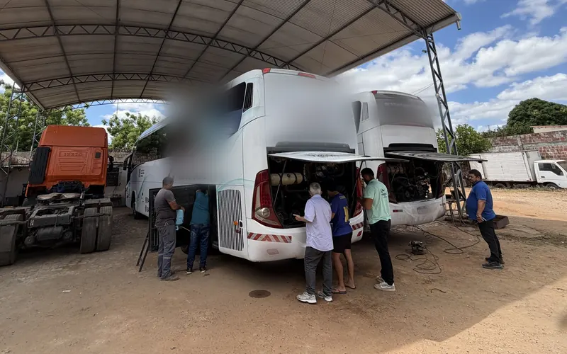 Equipe da JS Eletrofrio trabalhando em um ônibus rodoviário com a traseira aberta, debaixo da cobertura metálica da oficina
