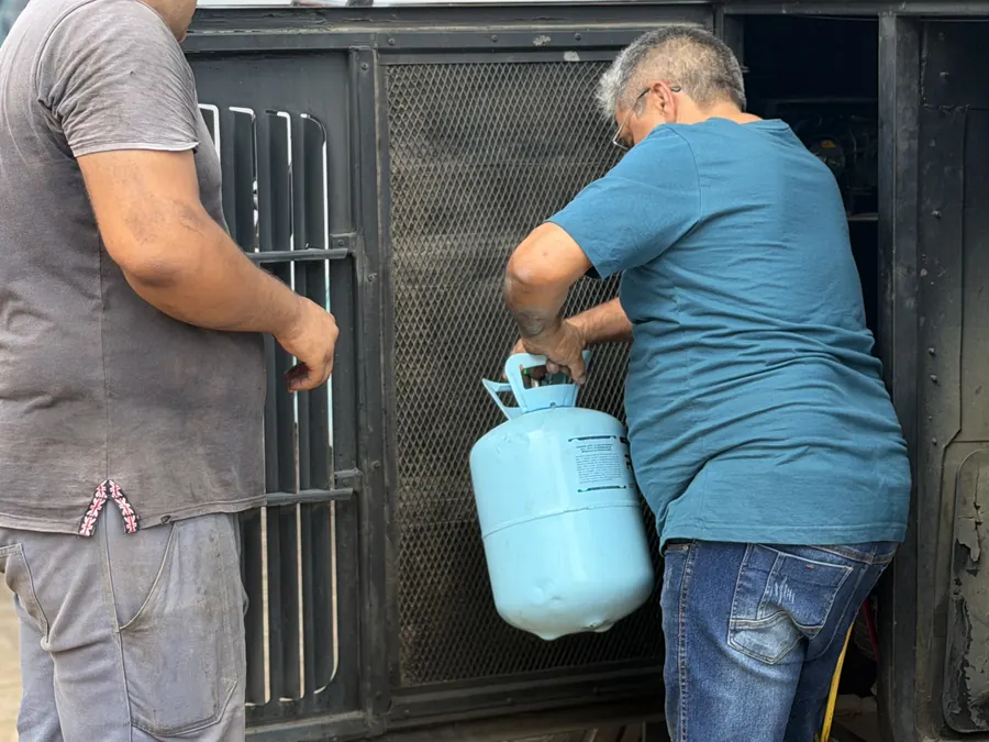Carga de gás no ar-condicionado de um ônibus na oficina da JS Eletrofrio, com o cilindro de gás junto ao compartimento lateral