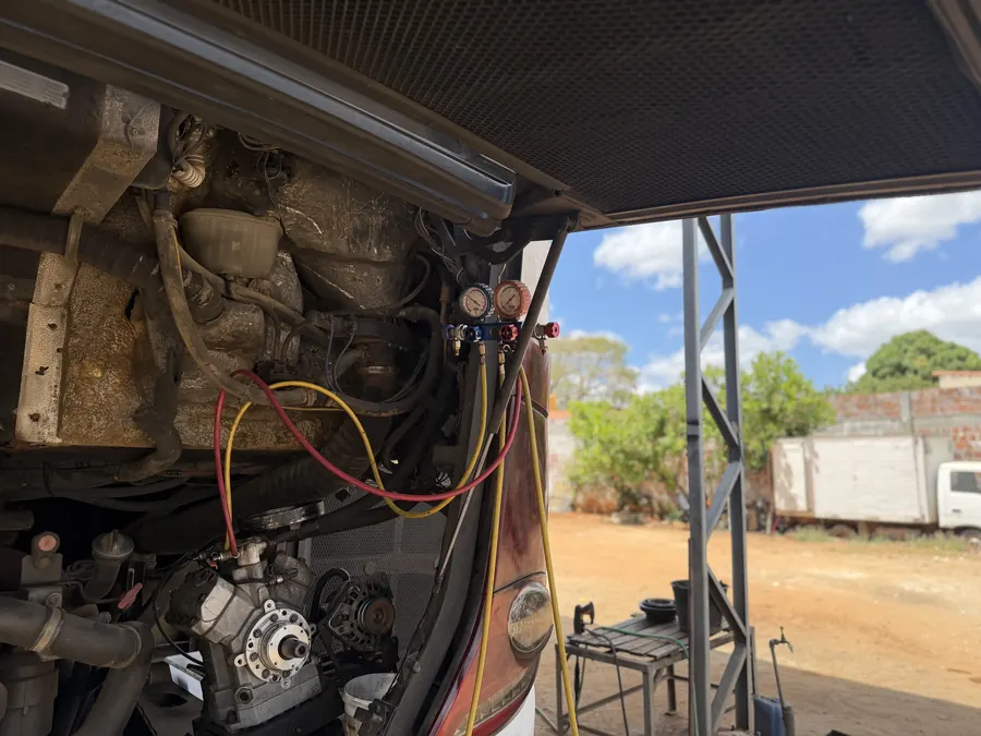 Manômetros do manifold ligados ao compressor do ar-condicionado de um ônibus, com as mangueiras de serviço conectadas
