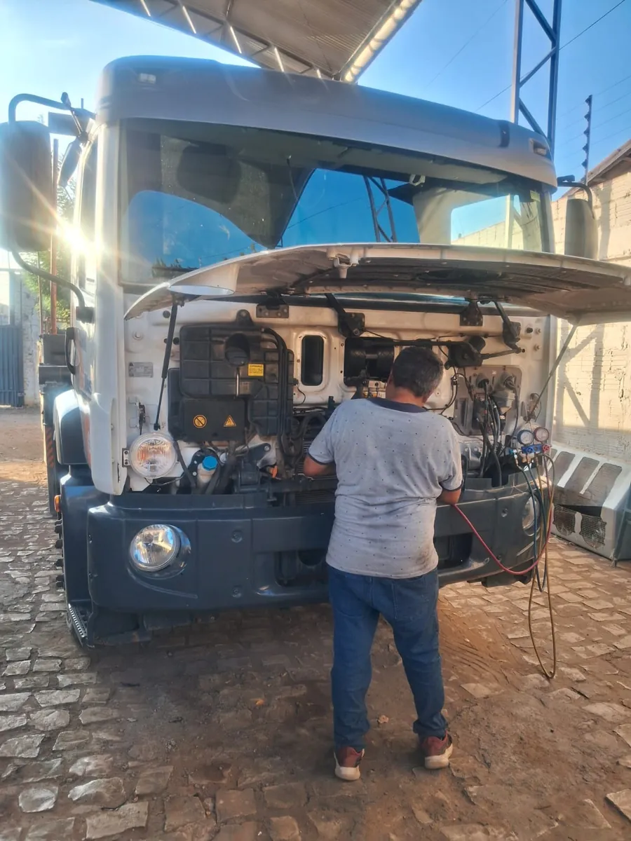 Técnico da JS Eletrofrio trabalhando na frente de um caminhão com a cabine basculada