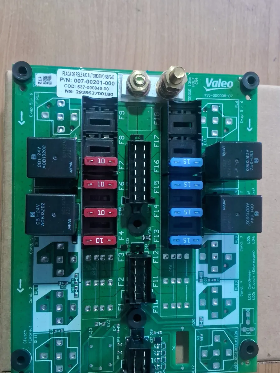Placa de comando elétrico Valeo de ar-condicionado de ônibus, com relés e fusíveis, sobre a bancada da oficina