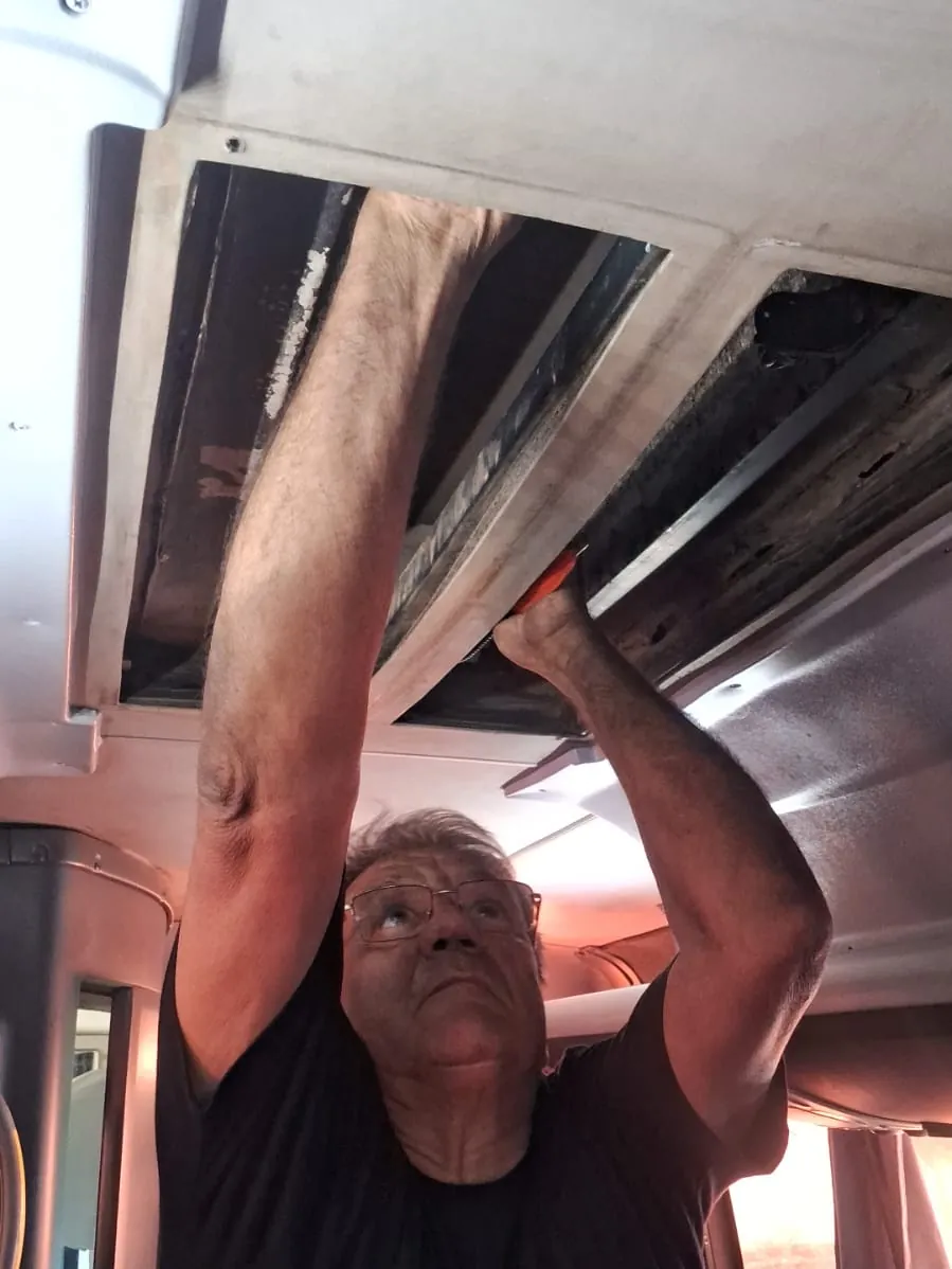 Técnico da JS Eletrofrio trabalhando no duto de ar-condicionado no teto interno de um ônibus